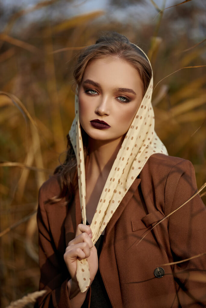 Kobieta w brązowym jesiennym płaszczu i chuście w grochy na głowie