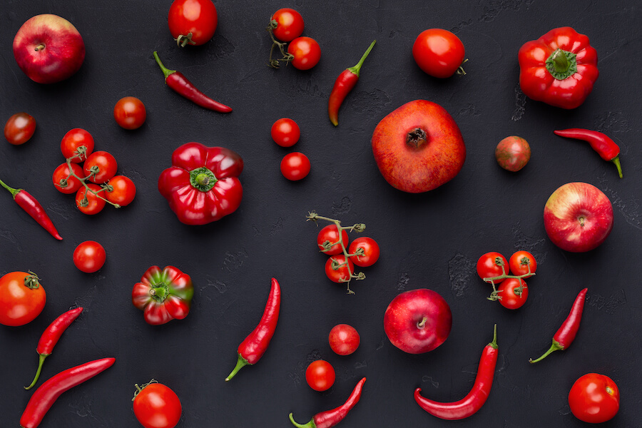 Owoce i warzywa na czarnym tle: pomidory, papryka, jabłka, granat