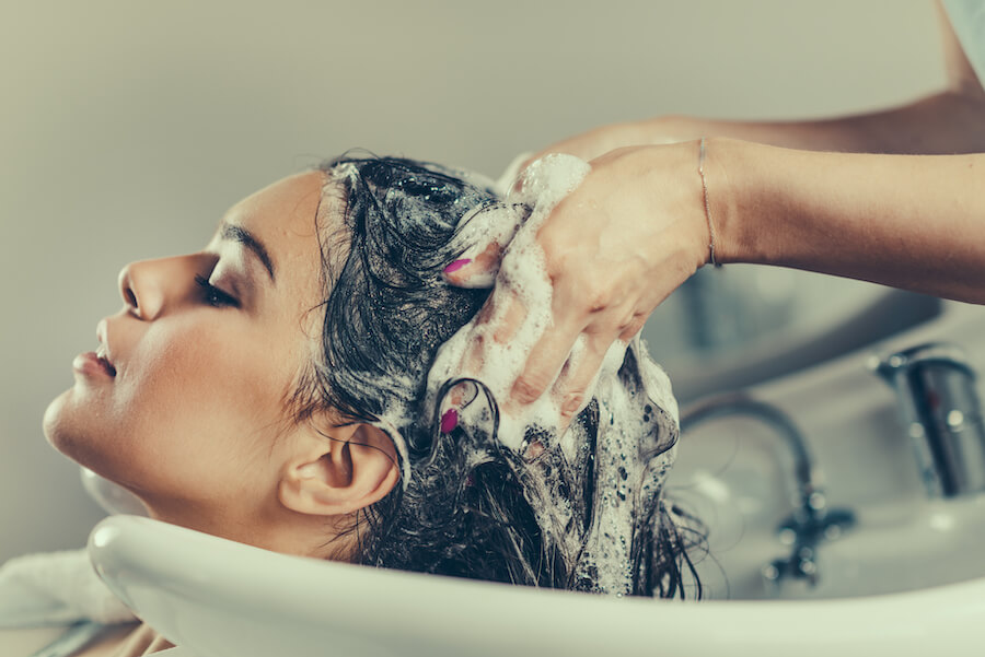 Kobieta podczas zabiegu mycia włosów w salonie