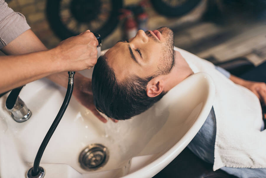 Mężczyzna podczas zabiegu mycia włosów w salonie